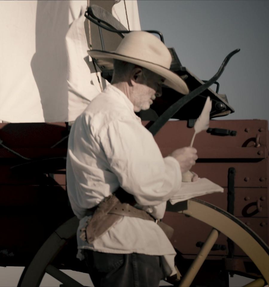 A hand writing a journal entry with a quill